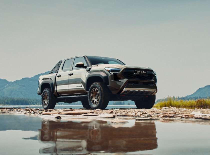 2025 Toyota Tacoma Hybrid Trailhunter in Bronze Oxide parked over wet and muddy terrain
