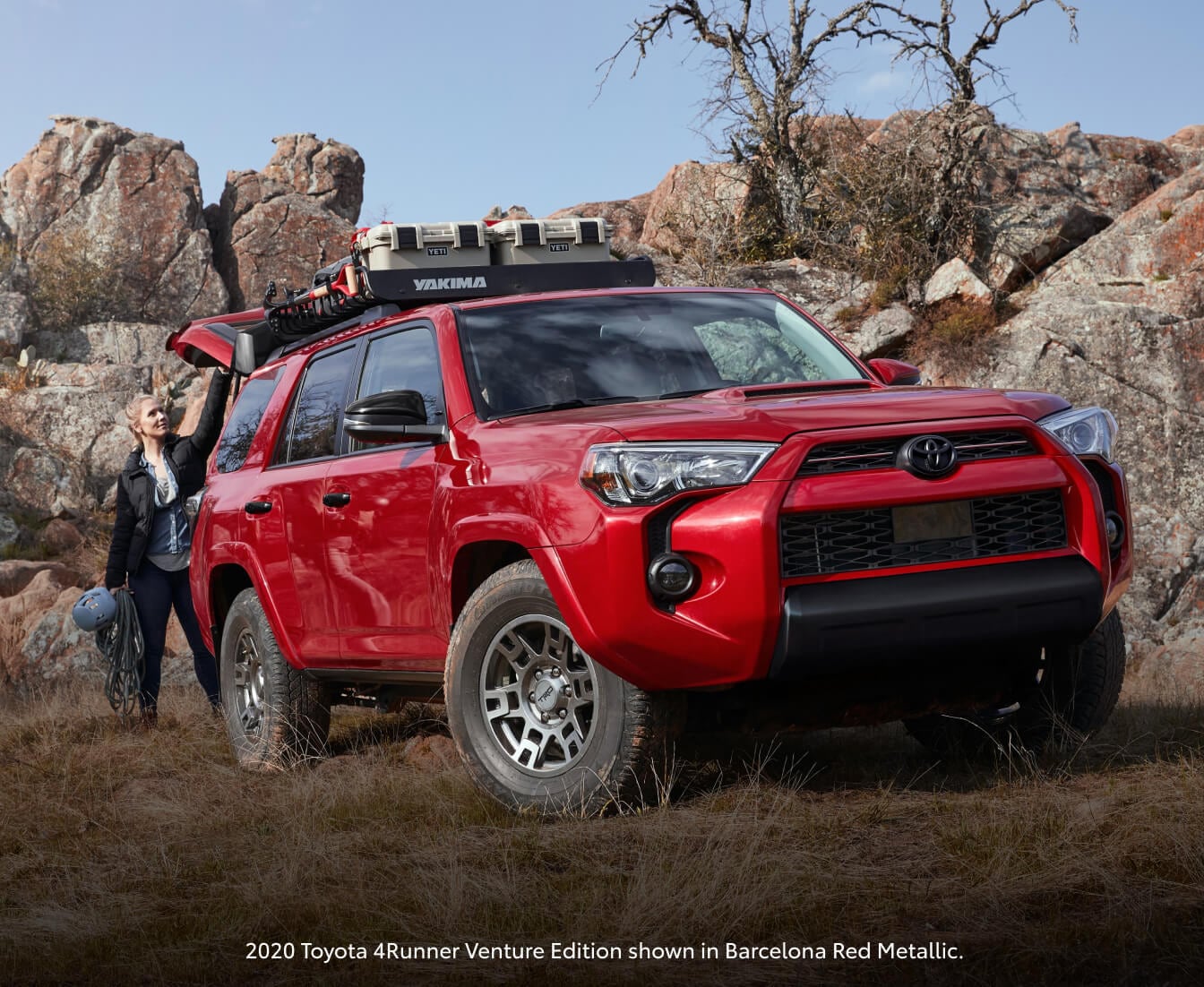 2020 Barcelona Red Metallic Toyota 4Runner Venture Edition parked on a rocky hill as a woman opens the rear hatch.