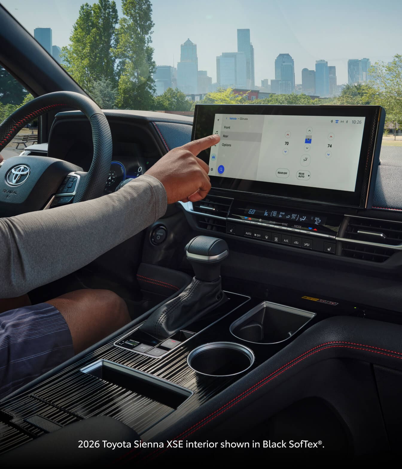 Interior dashboard of the 2026 Toyota Sienna XSE showing the driver using the touchscreen infotainment