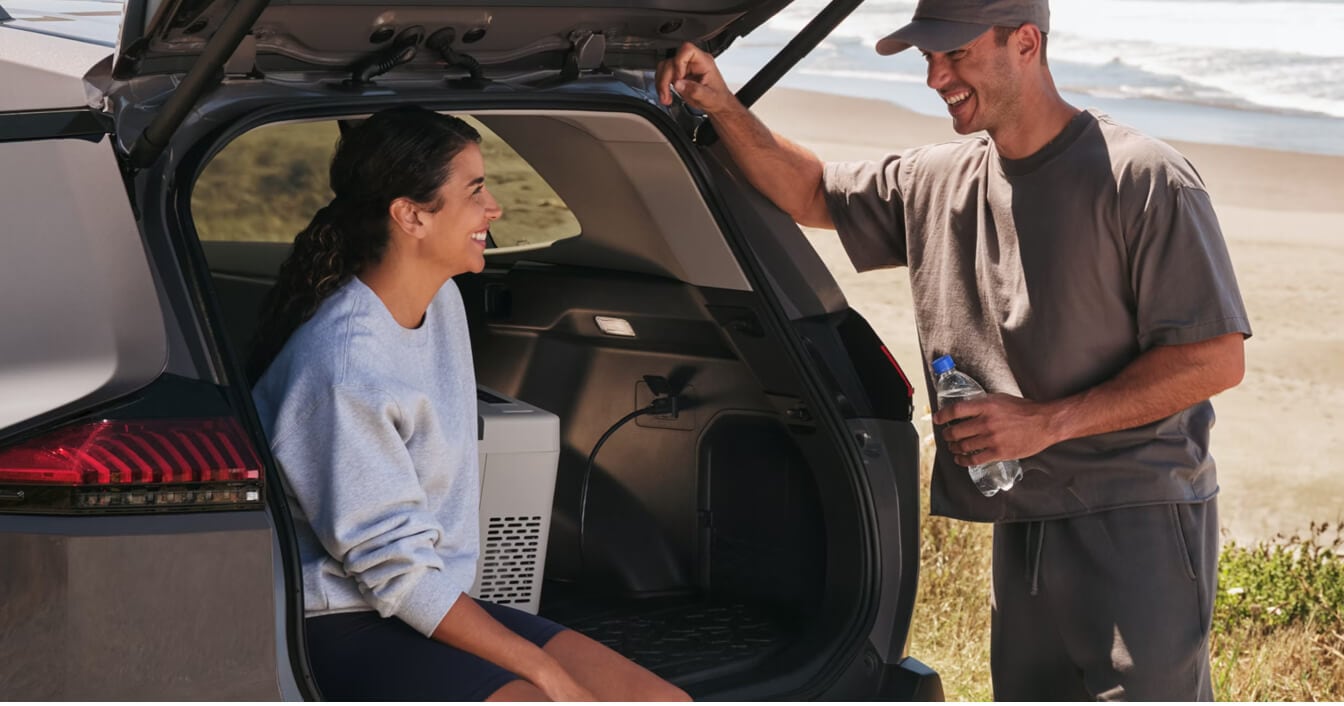 Close-up of a happy couple by the open cargo liftgate of a Urban Rock Grey Toyota RAV4 Plug-In Hybrid Woodland Edition.