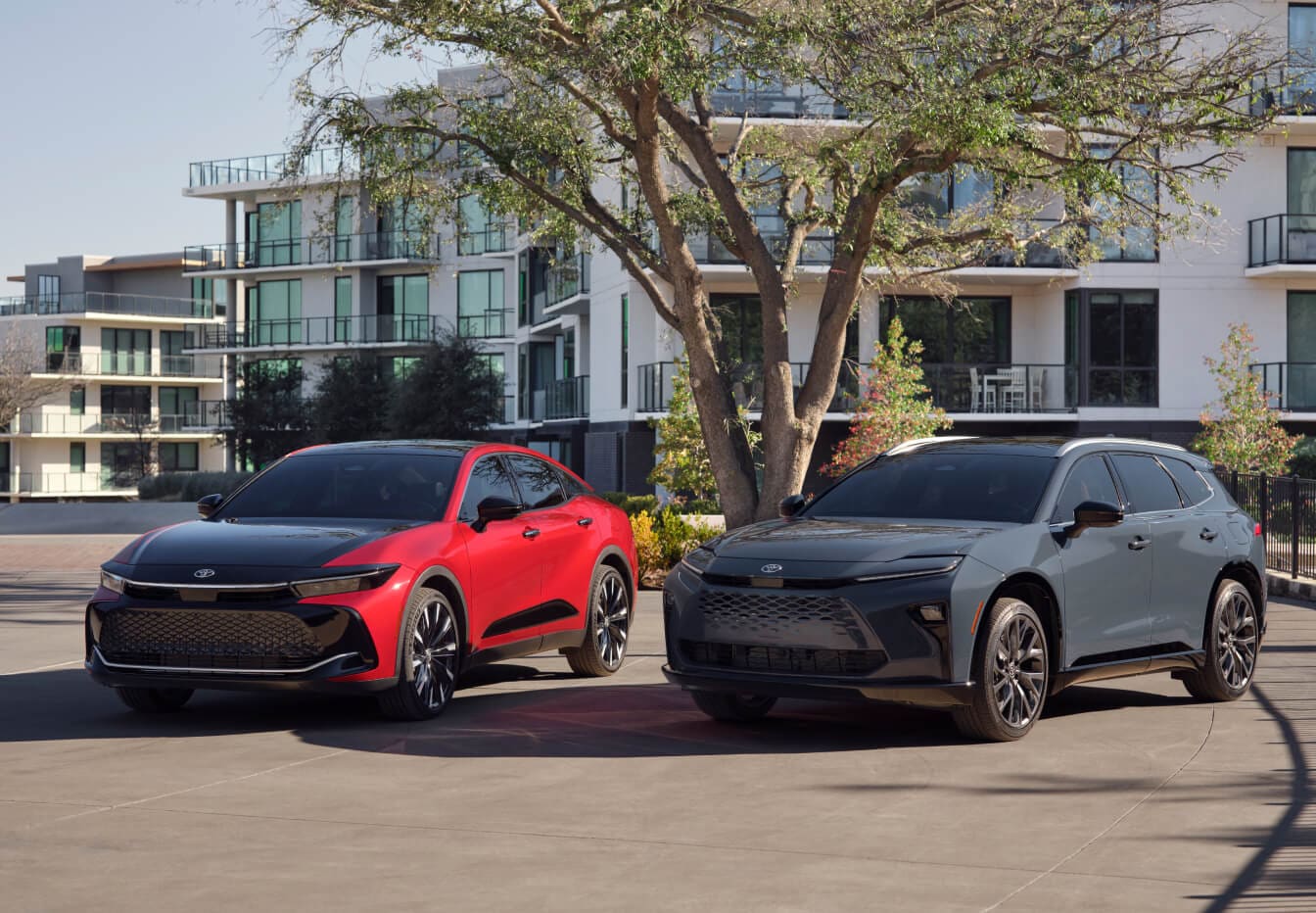 A red 2023 Toyota Crown and gray Toyota RAV4 parked near an apartment building.