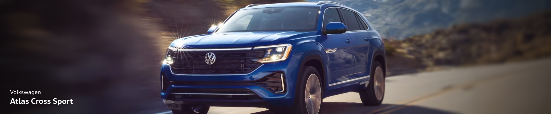 2026 Volkswagen Atlas Cross Sport in Mountain Lake Blue driving on a road with a blurry background