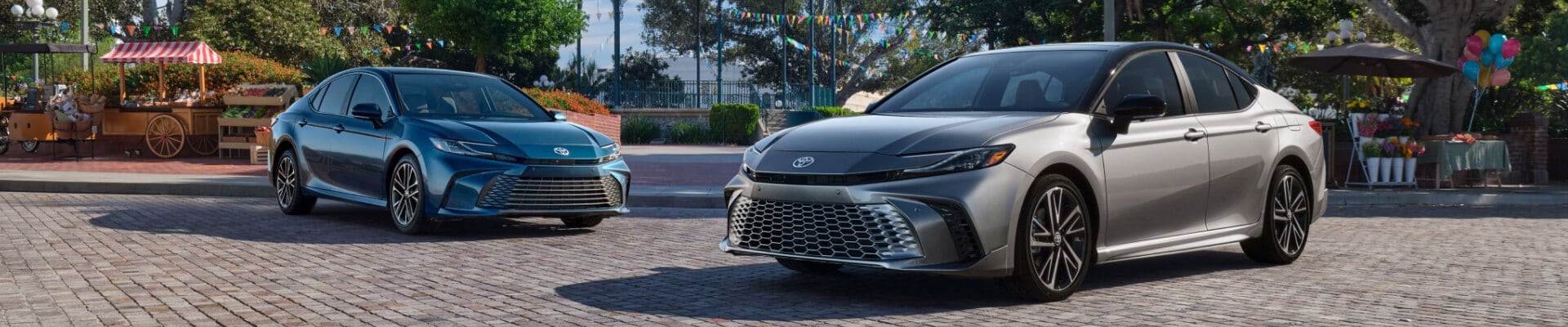 Toyota Camry XLE shown in Ocean Gem parked next to a Toyota Camry XSE shown in Heavy Metal with Midnight Black Metallic roof