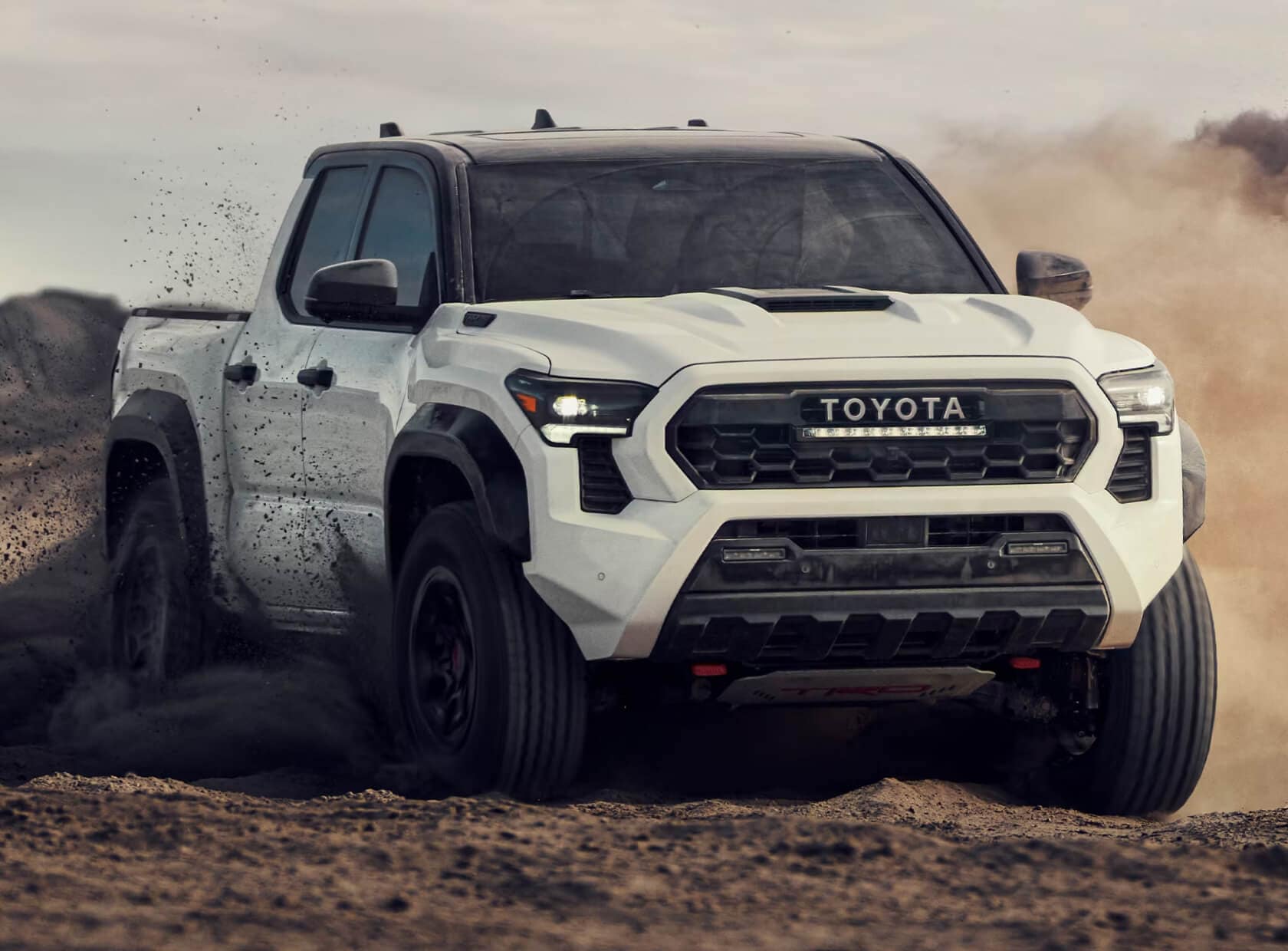 Toyota Tacoma TRD Pro in Ice Cap with a black roof off-roading on rocky terrain