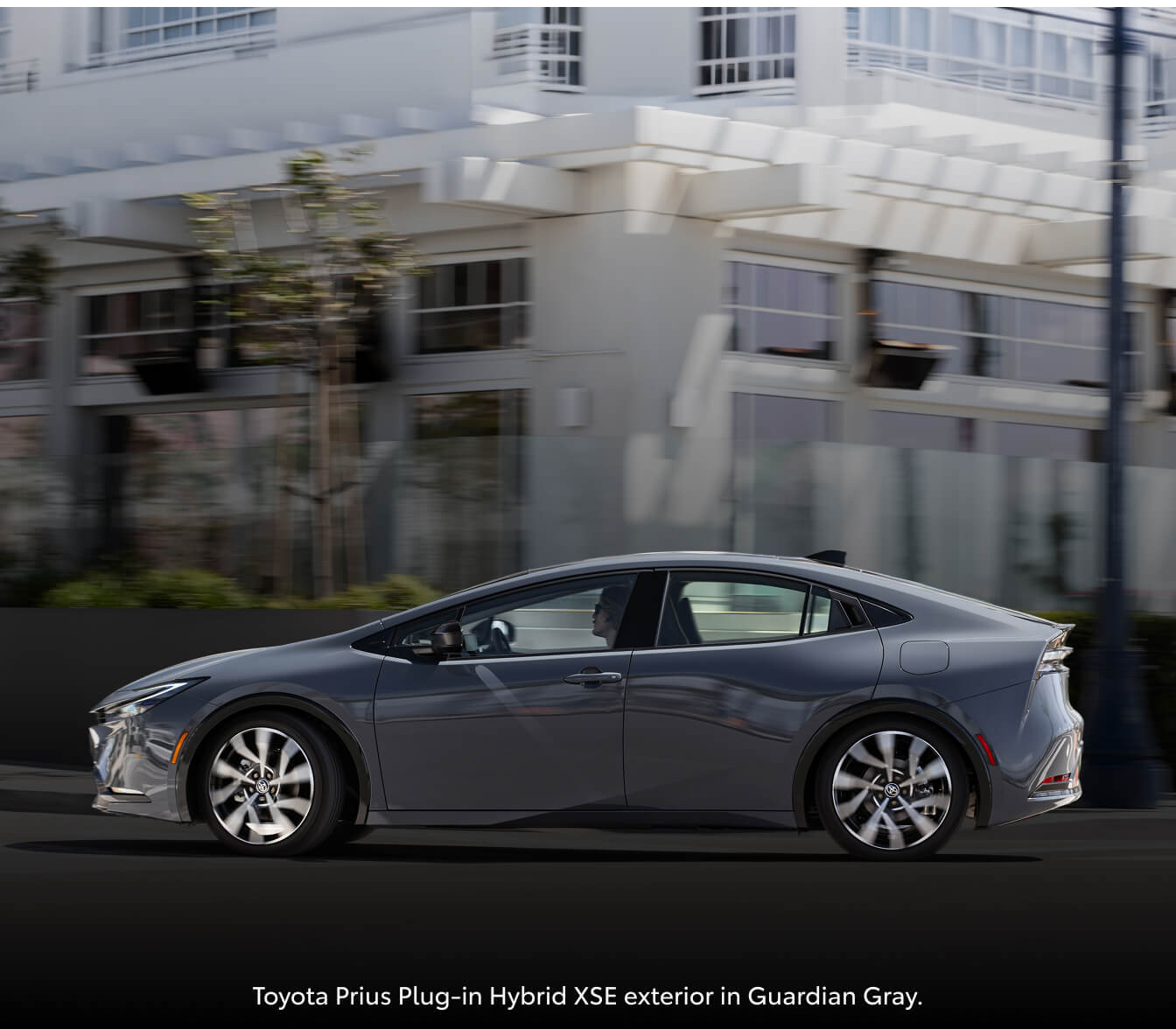 Toyota Prius Limited driving past a white city building.