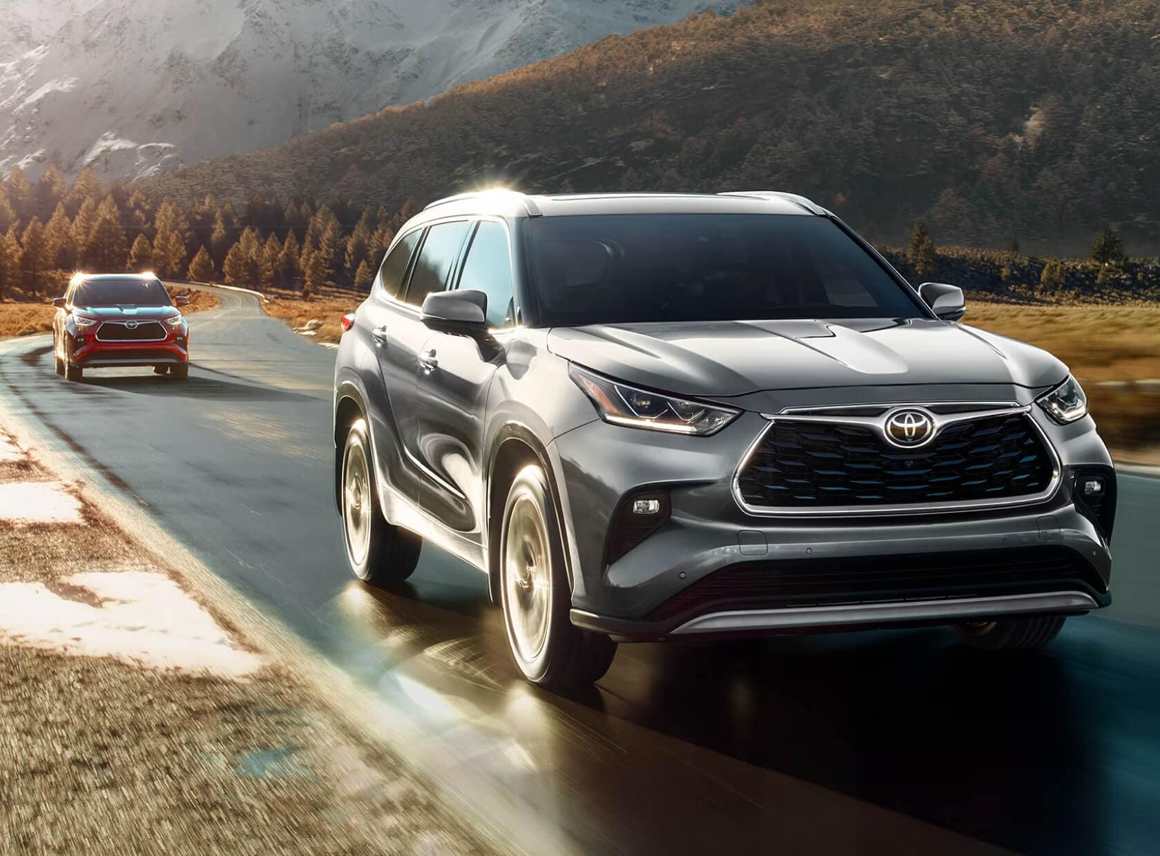 Toyota Highlander Platinum AWD in Celestial Silver Metallic driving on a winding road at sunrise