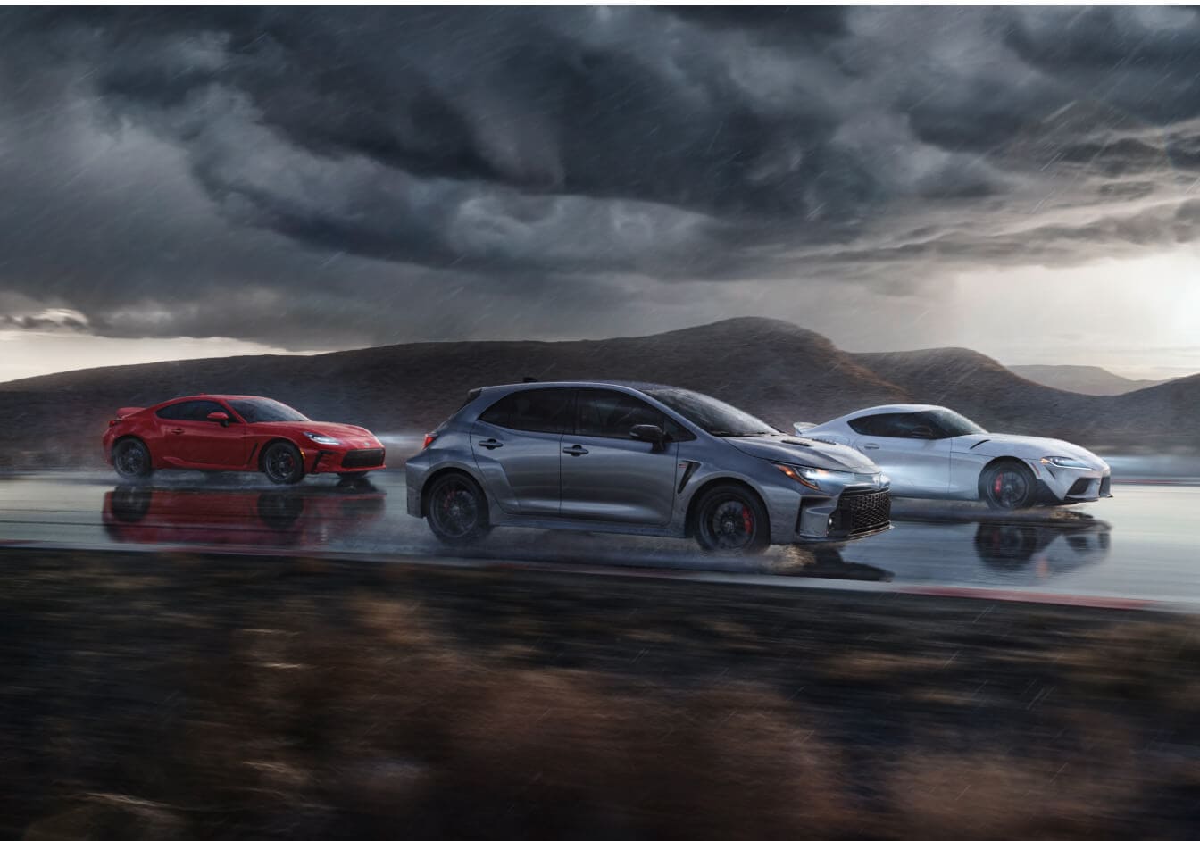 A 2023 Toyota GR86, Supra and GR Corolla Hatchback driving down a rainy highway.