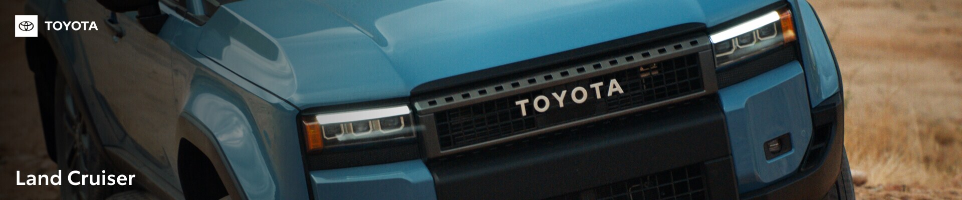 Close-up front view of a Toyota Land Cruiser in Heritage Blue highlighting its retro grille and LED headlights.