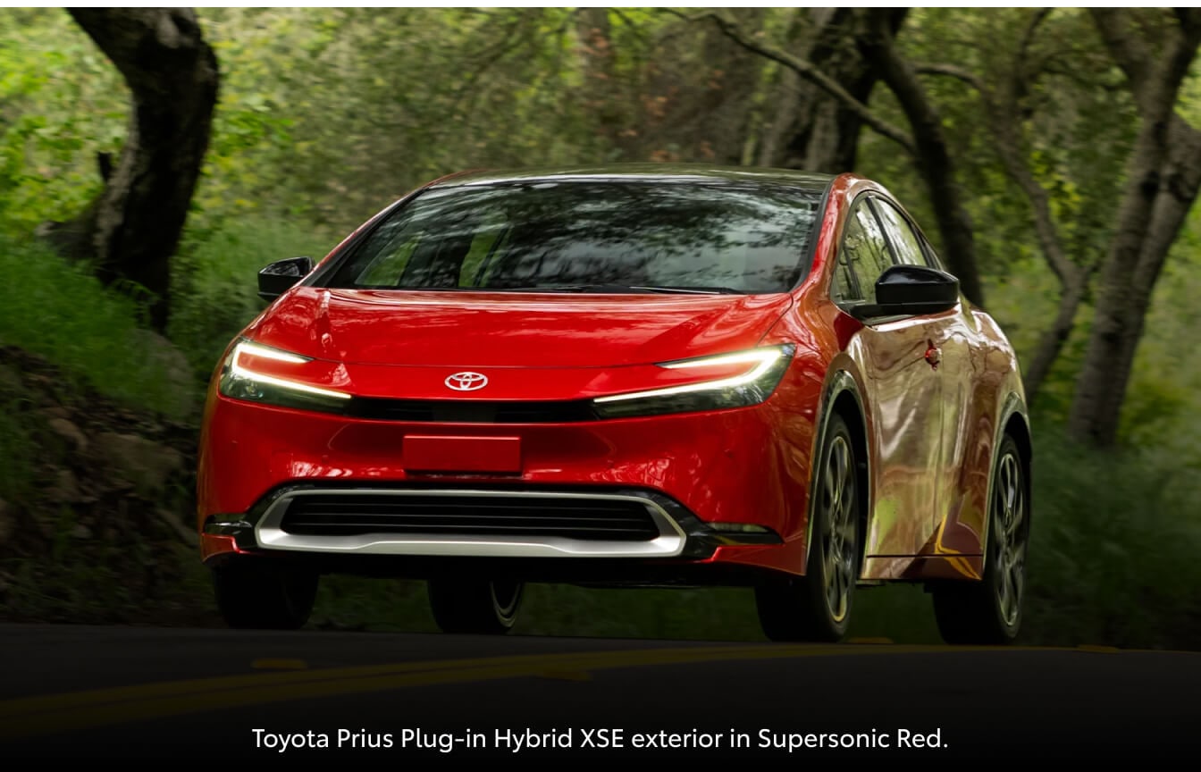 Toyota Prius Limited driving on a tree-lined asphalt road.
