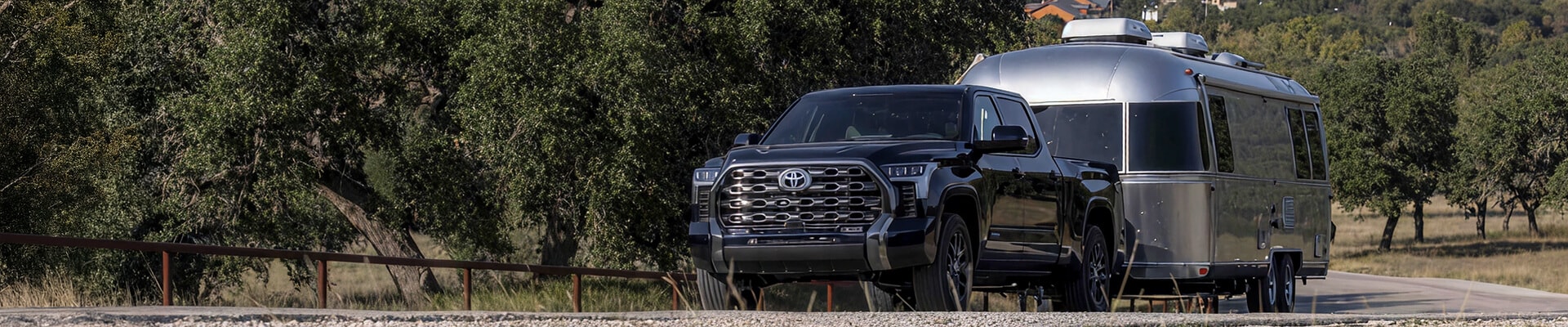 2025 Toyota Tundra Platinum in Blueprint towing an Airstream in a wooded area