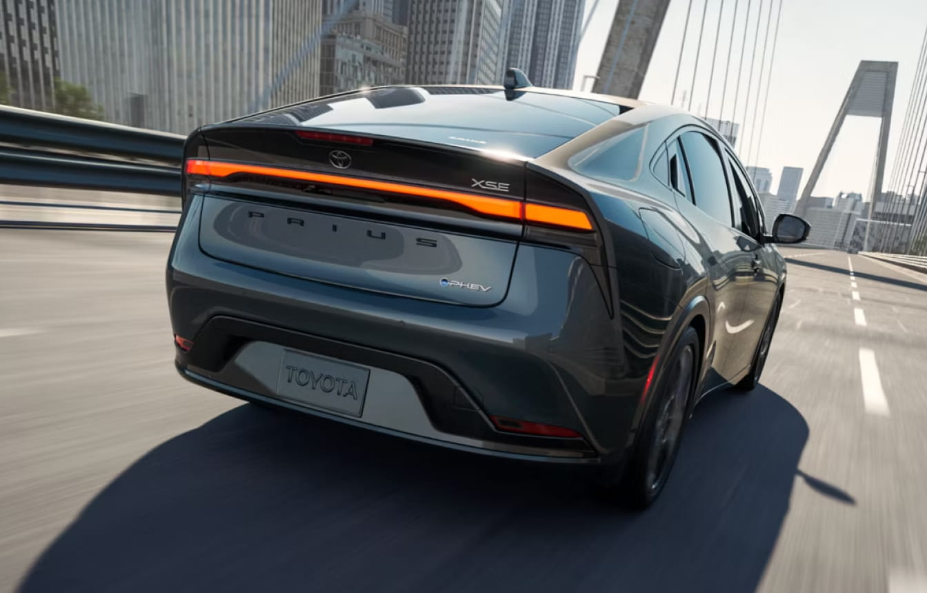 Toyota Prius Plug-in Hybrid XSE driving across a city bridge, shown from a rear three-quarter view.