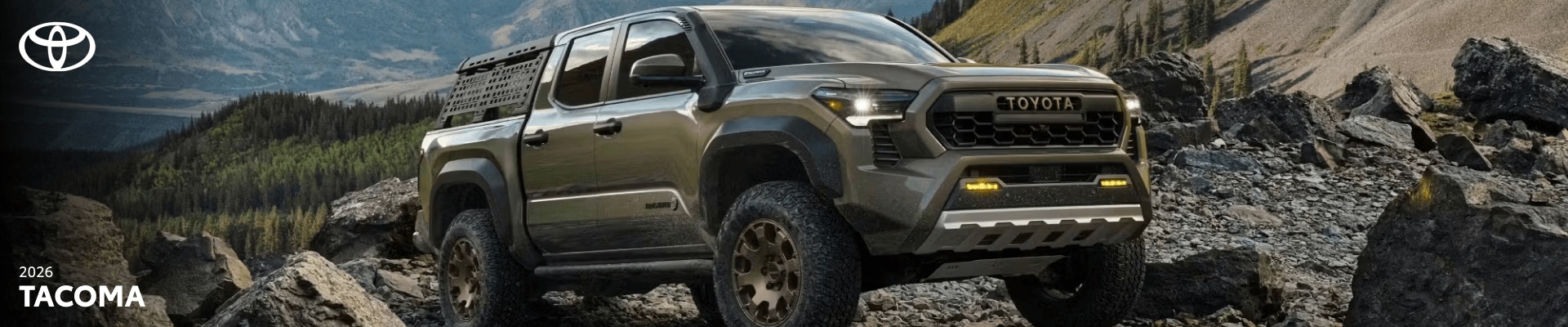 2026 Toyota Tacoma Trailhunter driving through off-road, mountainous terrain