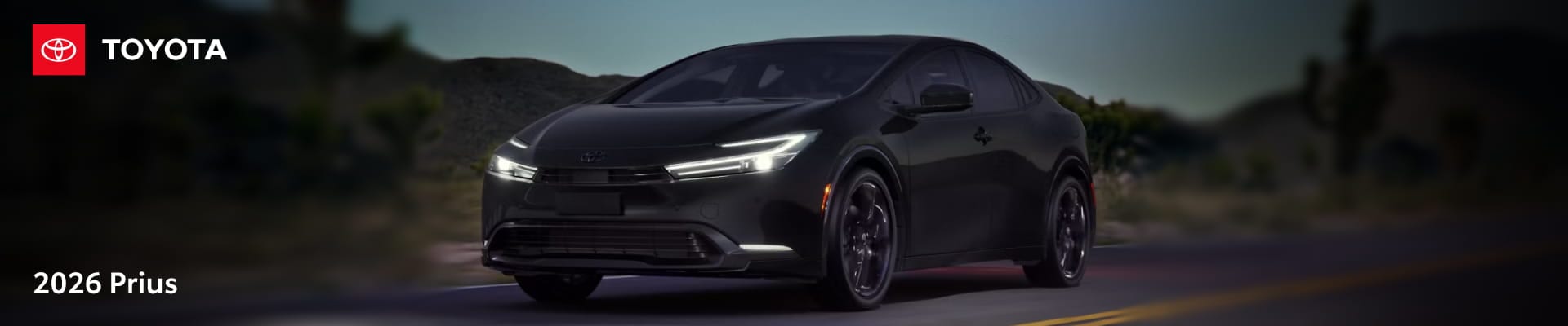 2026 Toyota Prius driving on a road at dusk with its LED headlights illuminated.
