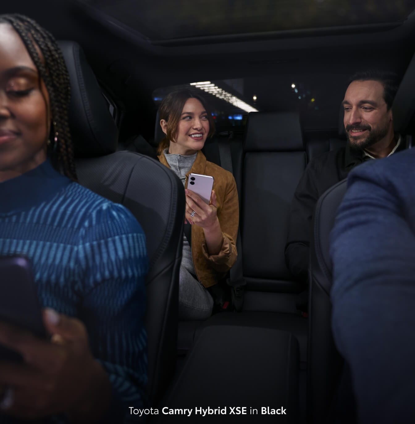 Four friends sitting inside of a new Toyota Camry Hybrid XSE with all black interior