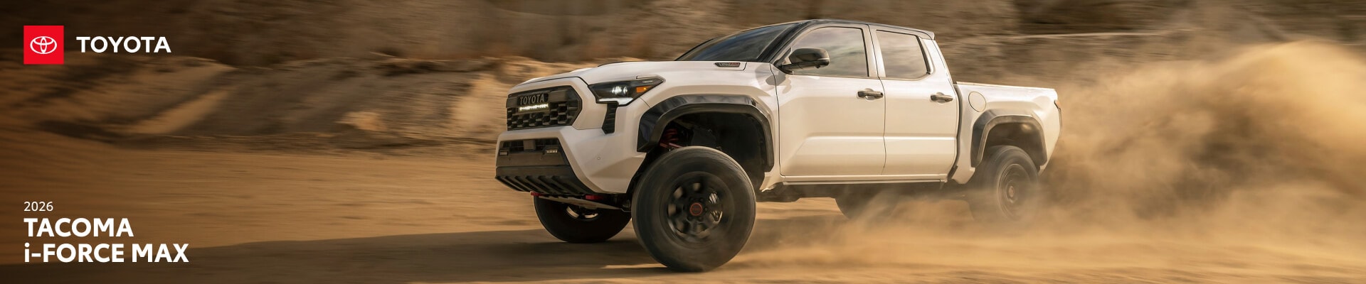 2026 Toyota Tacoma TRD Pro i-FORCE MAX in Ice Cap with black roof, front three-quarter view kicking up dust off-road.