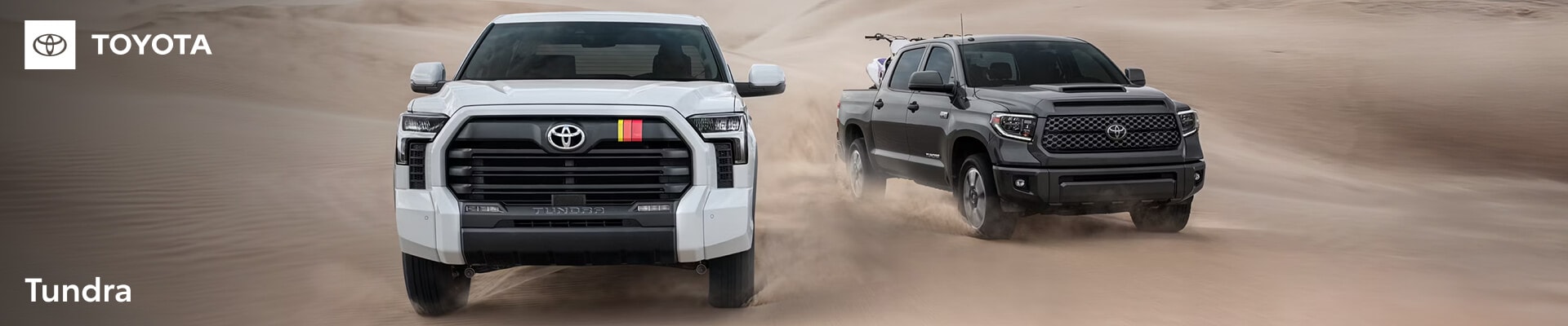 2026 Toyota Tundra SR5 Trucks driving side-by-side in sand. One white white and one gray.