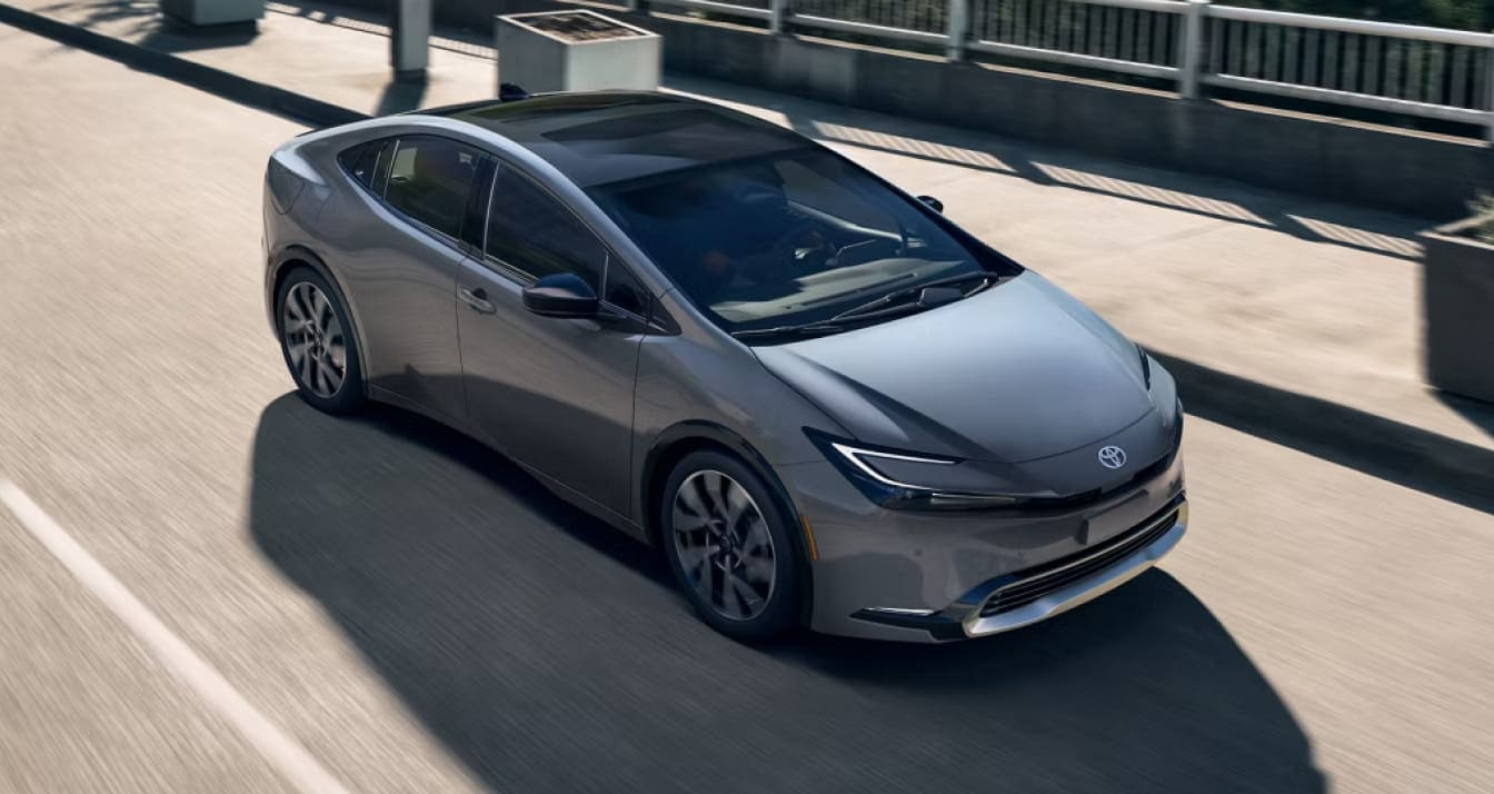 2026 Toyota Prius driving on a city road, shown from an elevated front three-quarter view.