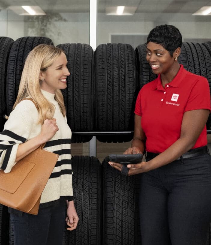 Toyota employee assisting a customer with new tires at a Toyota tire shop