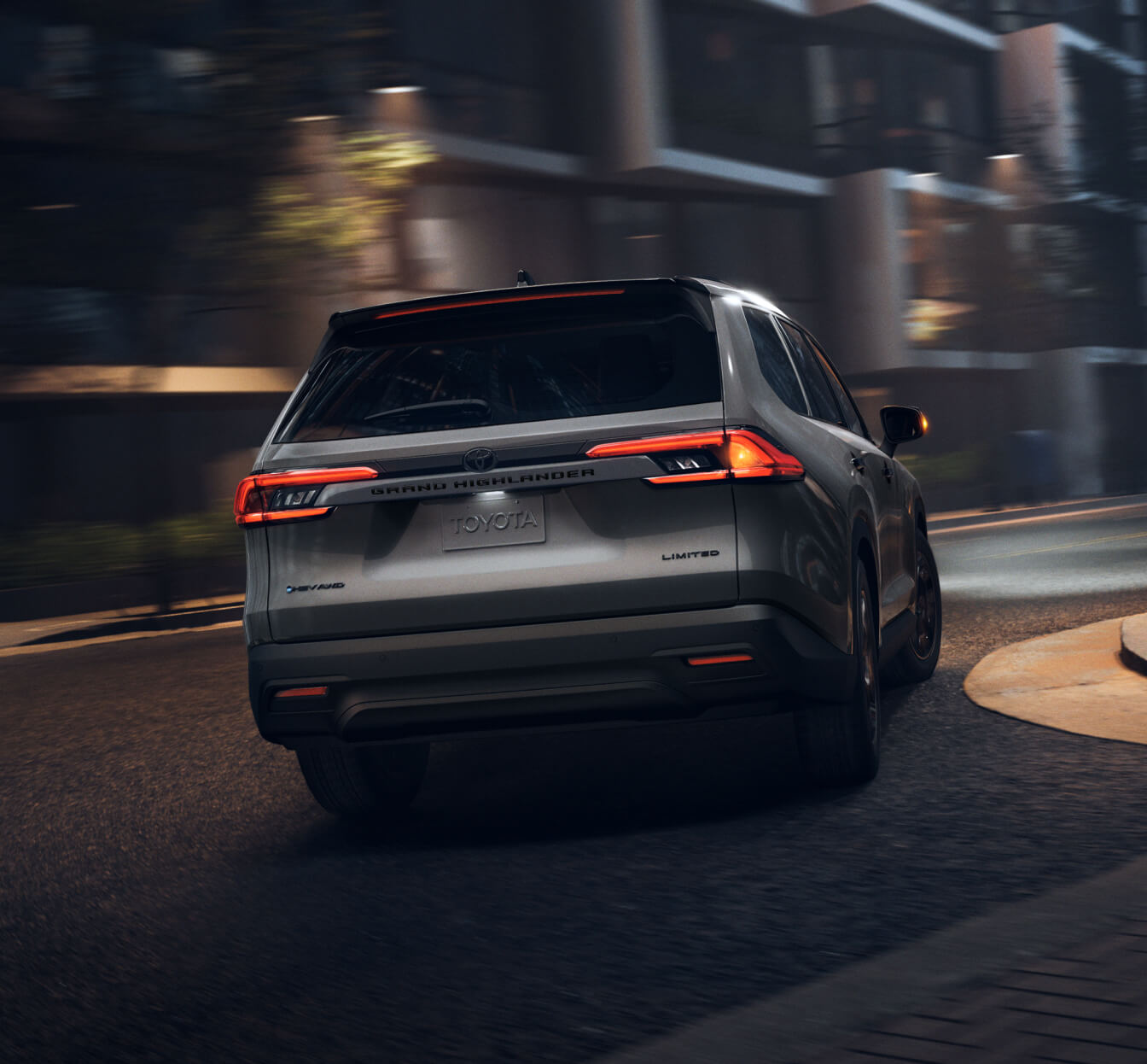 2026 Toyota Grand Highlander Hybrid Limited AWD driving away on a dimly lit street