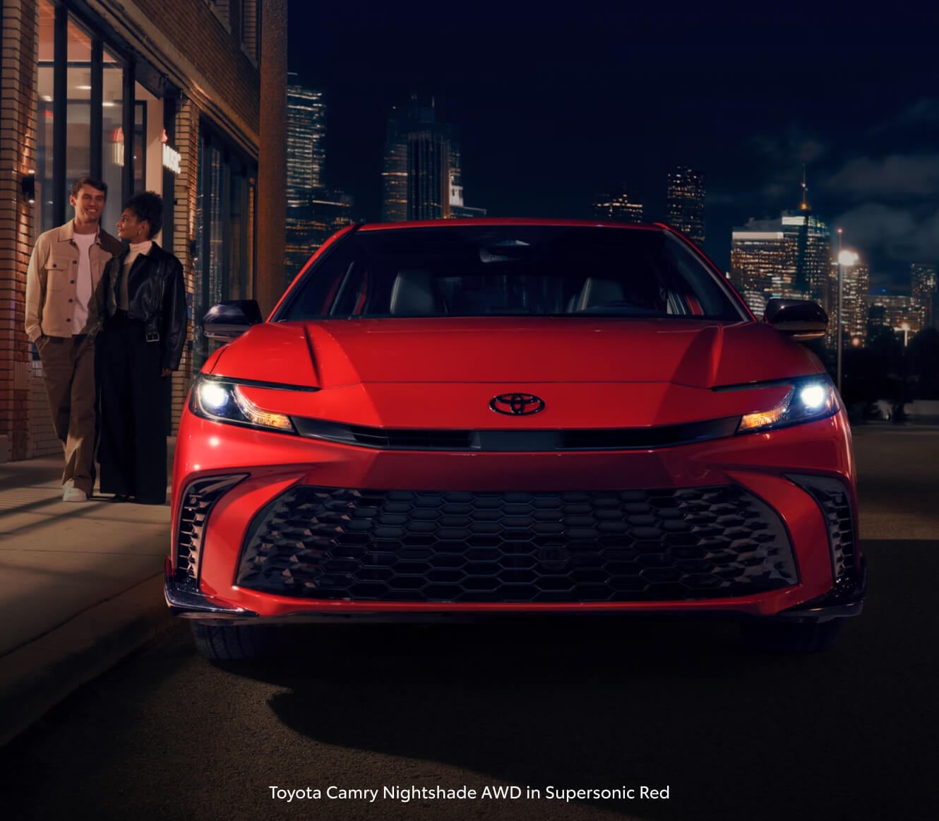 2026 Toyota Camry Nightshade AWD in Supersonic Red parked on a city street