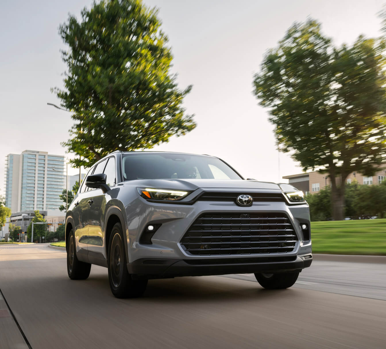 Passenger-side three-quarter view of a grey 2026 Toyota Grand Highlander Nightshade driving on a road.