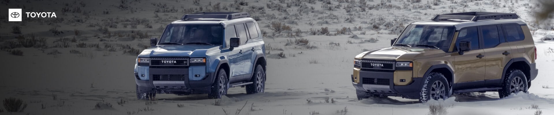 Toyota Land Cruiser First Edition in Heritage Blue and Trail Dust with roof racks on snowy terrain.