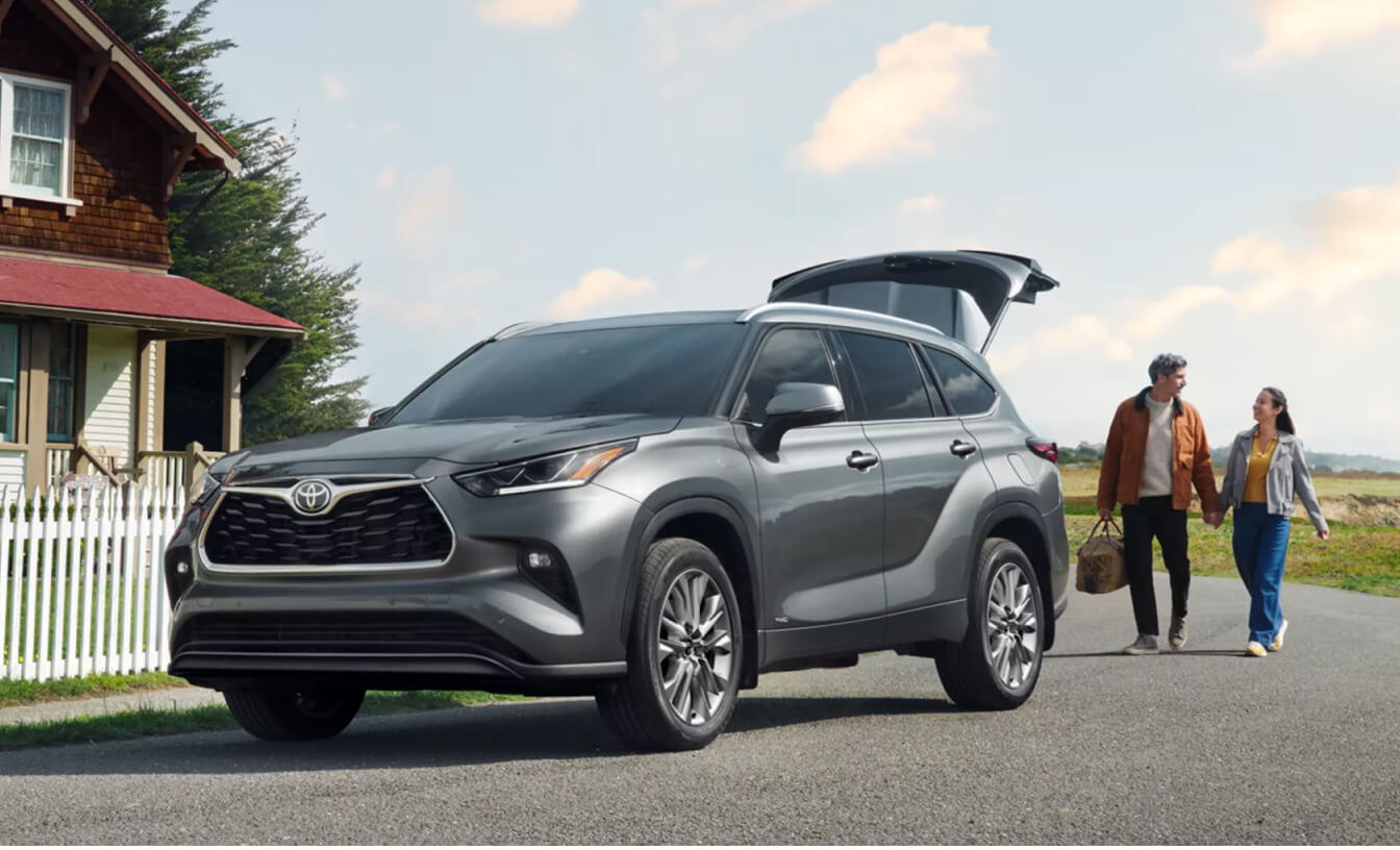 Front quarter view of a 26 Toyota Highlander Limited in Heavy Metal with open tailgate by a coastal home.