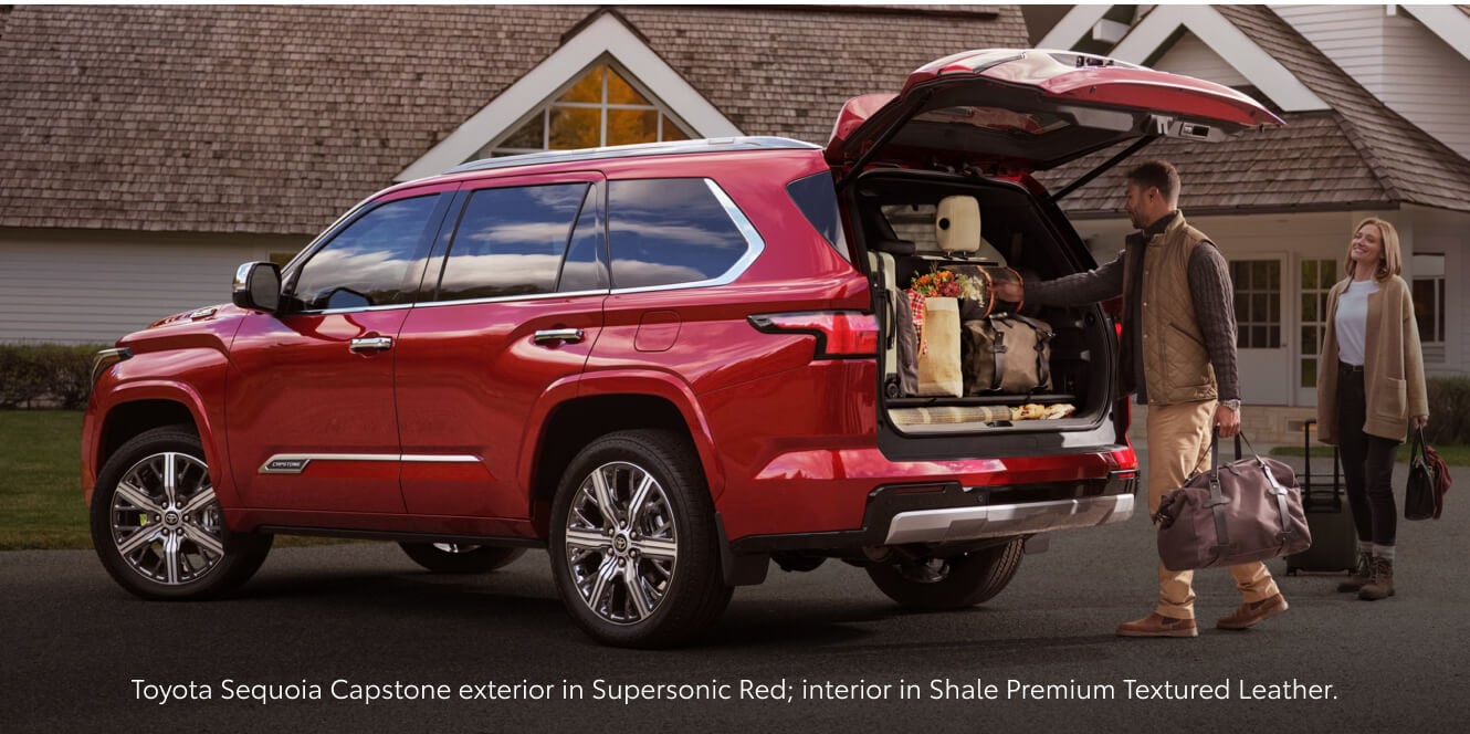 Rear-three-quarter view of a 2026 Red Toyota Sequoia Capstone being loaded with luggage.