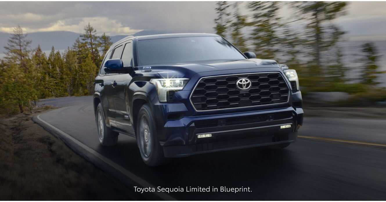 Low-angle front view of a 2026 Blue Toyota Sequoia Limited driving along a winding mountain.