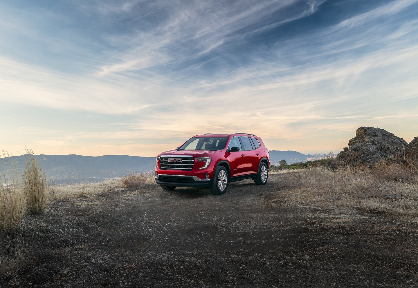Red GMC Acadia parked by sunset view