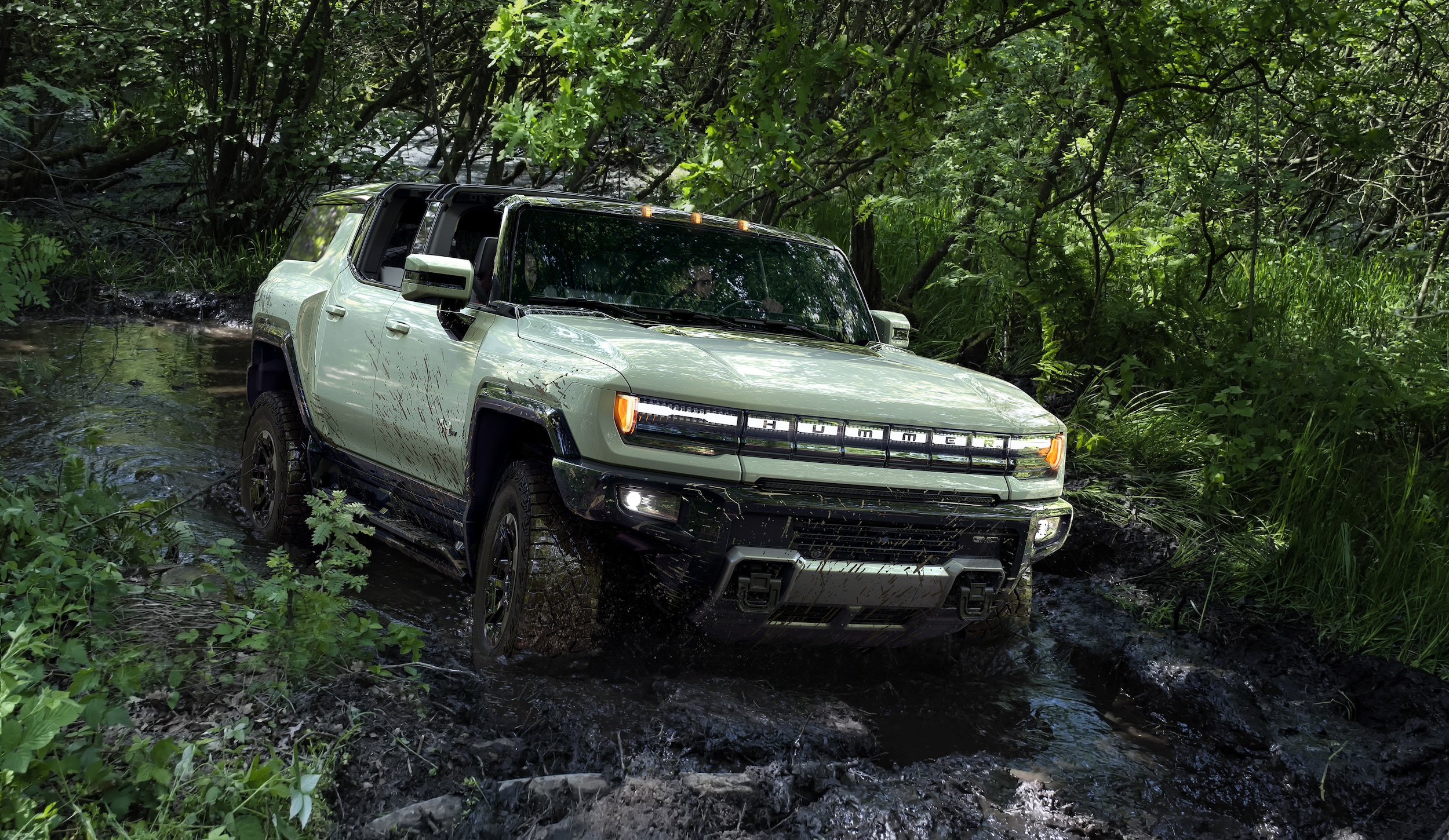 GMC Hummer EV SUV driving through stream