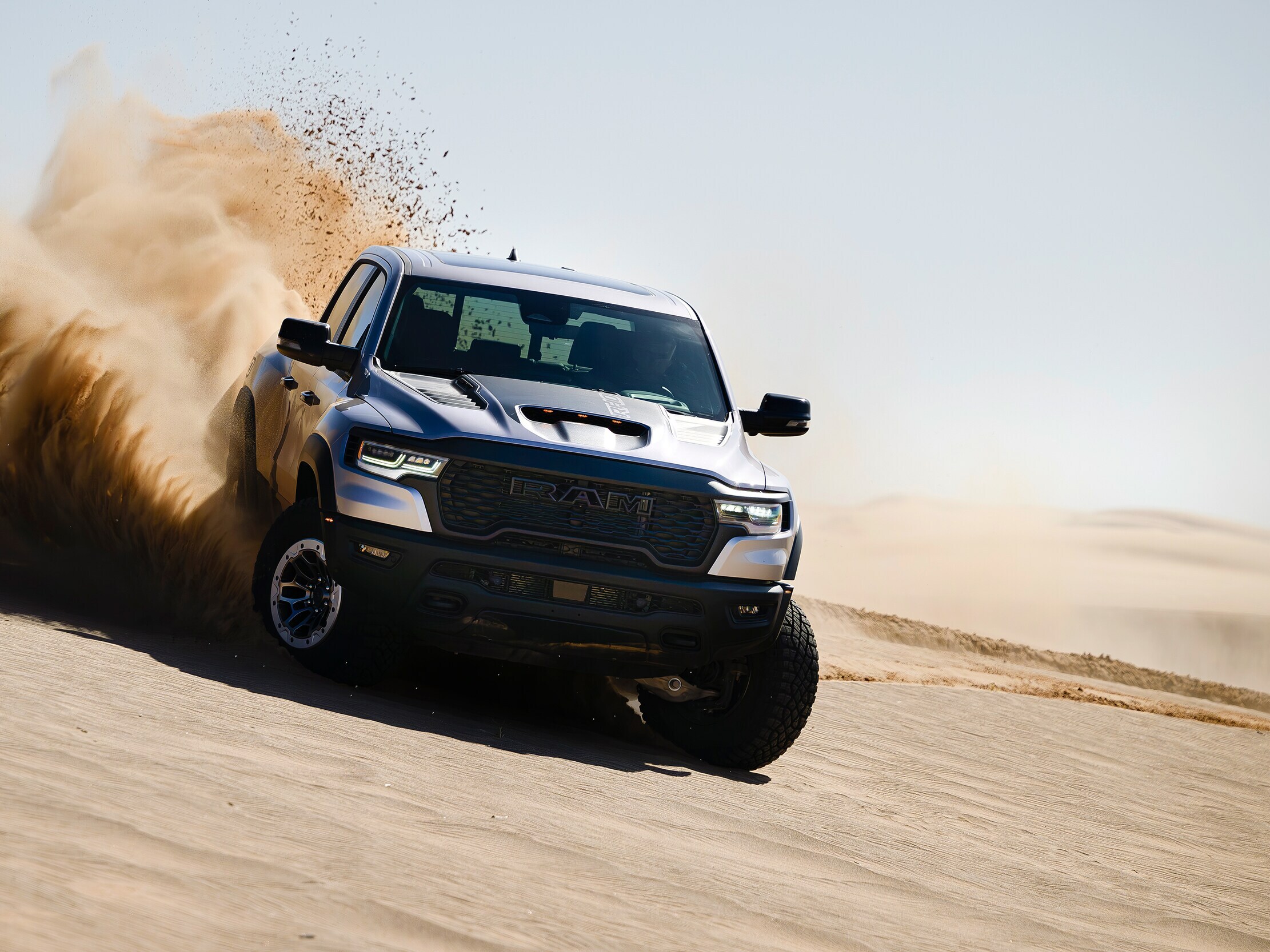Blue Ram 1500 driving through sand