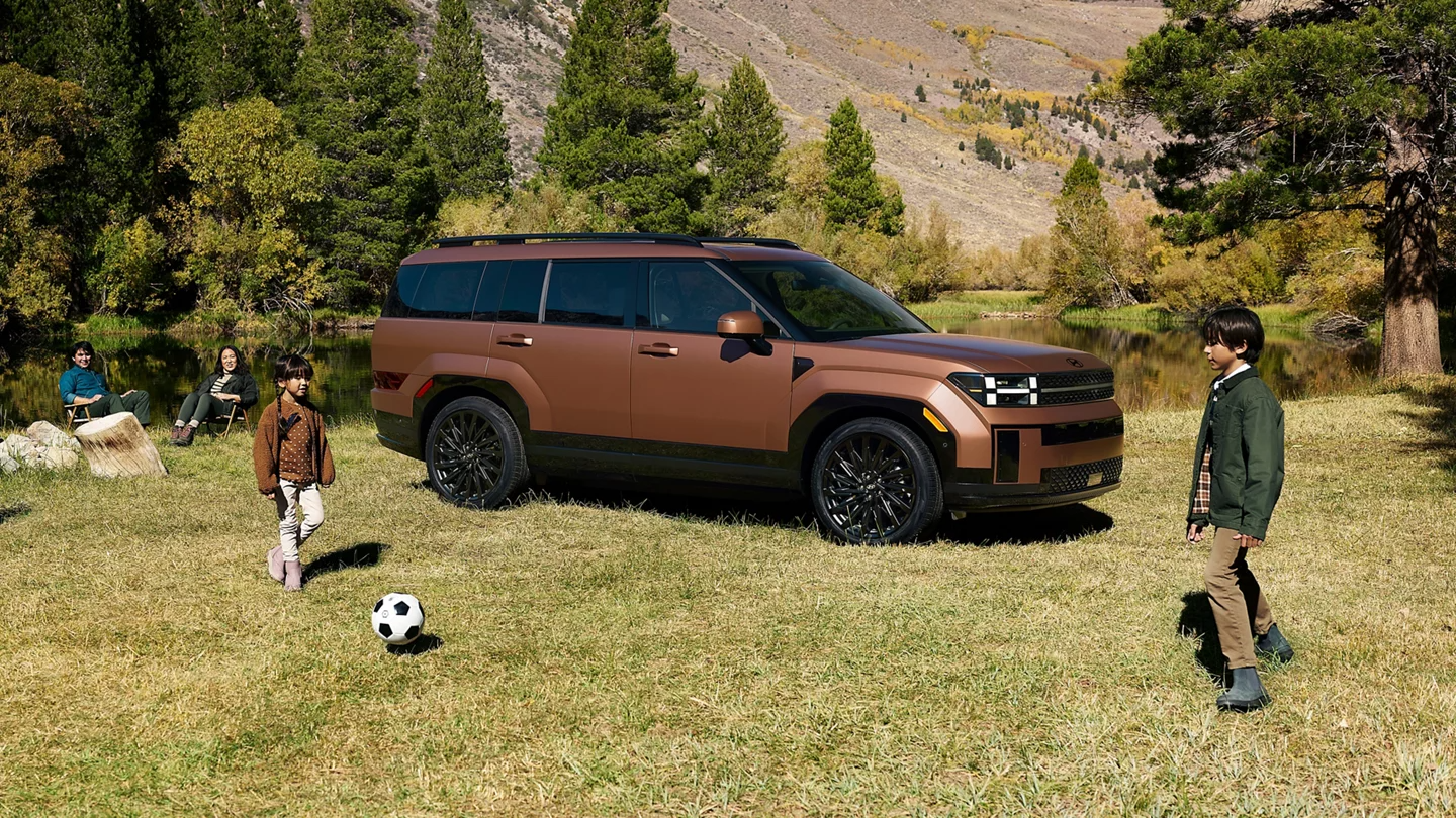 Family playing soccer near a Hyundai Santa Fe Hybrid