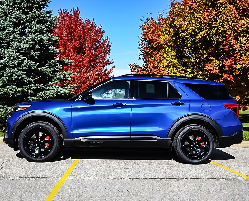 2020 Blue Ford Explorer side exterior parked in a parking lot in front of trees