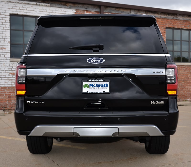 2019 black Ford Expedition rear tailgate parked next to brick building