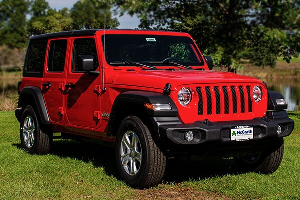 2020 Red Jeep Wrangler parked in a park area next to trees and pond