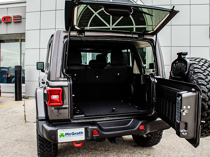 2021 Jeep Wrangler parked next to McGrath Chrysler Jeep Dodge Ram with rear tailgate open