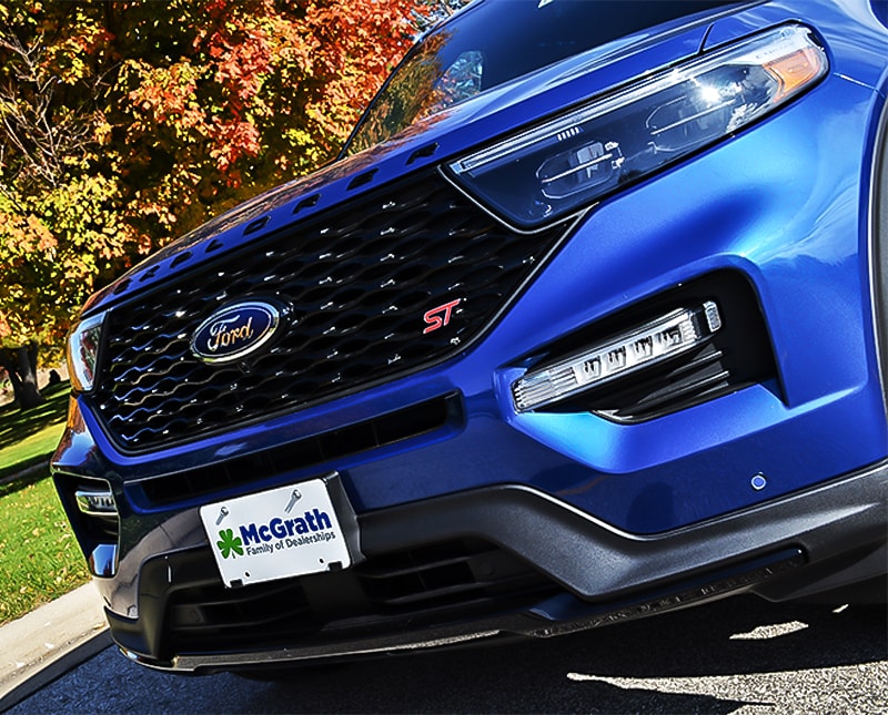2020 Blue Ford Explorer front grille parked in front of trees