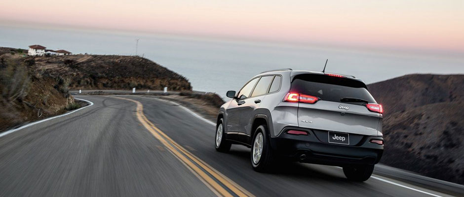Silver Jeep Cherokee driving on a road