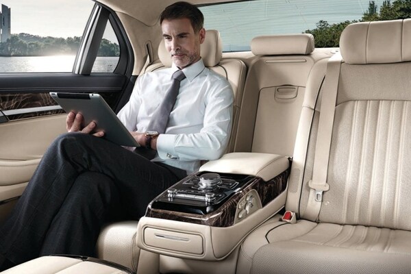 Man on a tablet in the rear cabin of the 2019 Genesis G90