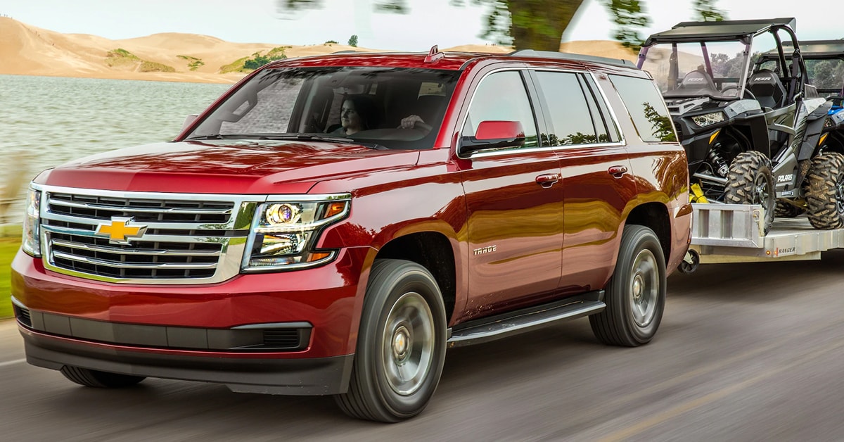 2019 Siren Red Chevy Tahoe towing a trailer of quads