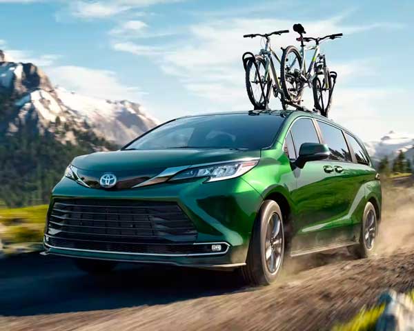 toyota sienna driving down the road with a roof rack with bikes