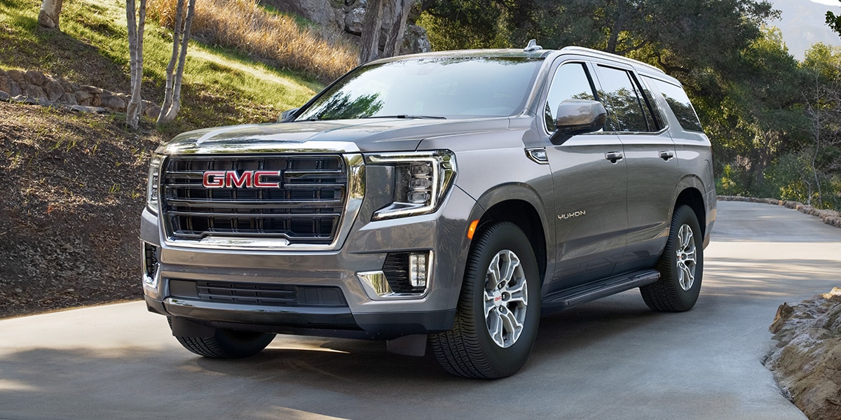 GMC Yukon SLE driving down the road in a wooded area