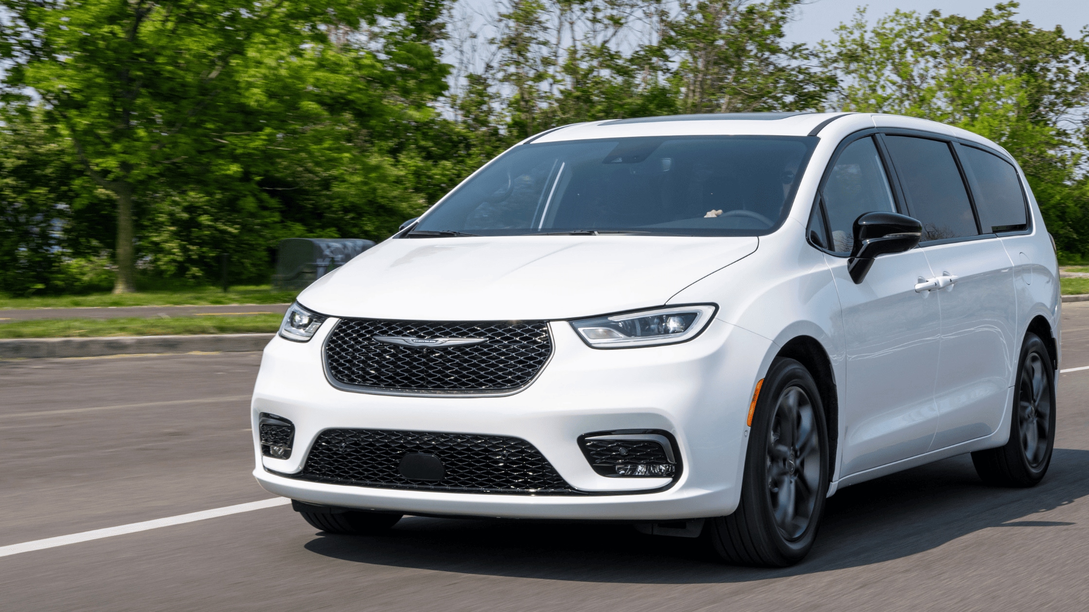White Chrysler Pacifica minivan driving on road, front view, daytime exterior