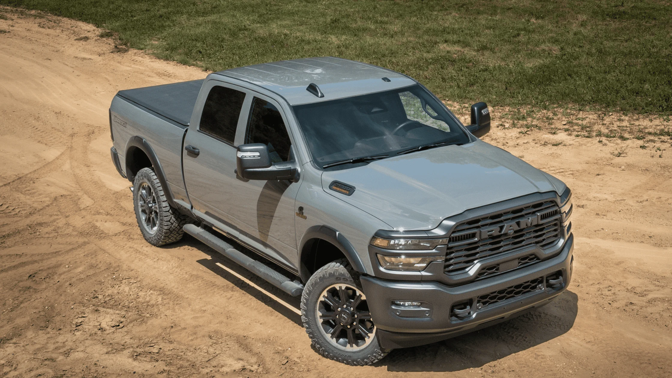Gray 2026 Ram Heavy Duty truck on a rugged dirt trail, featuring off-road tires, strong body lines, and a powerful front fascia ideal for tough terrain.