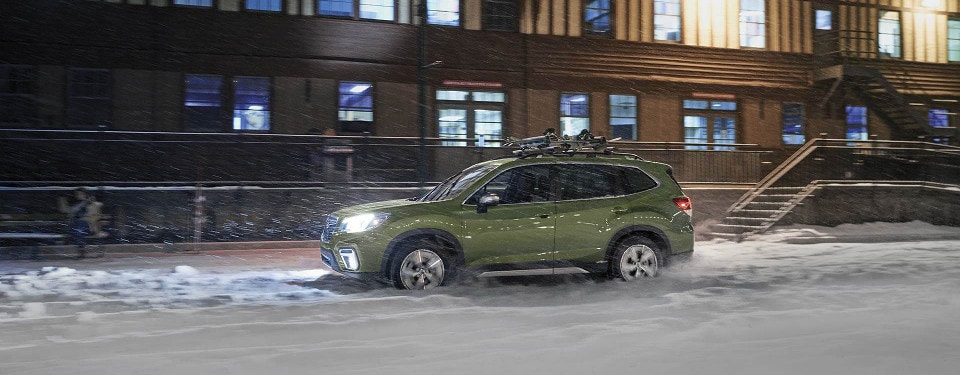 A green 2019 Subaru Forester driving through a snow storm