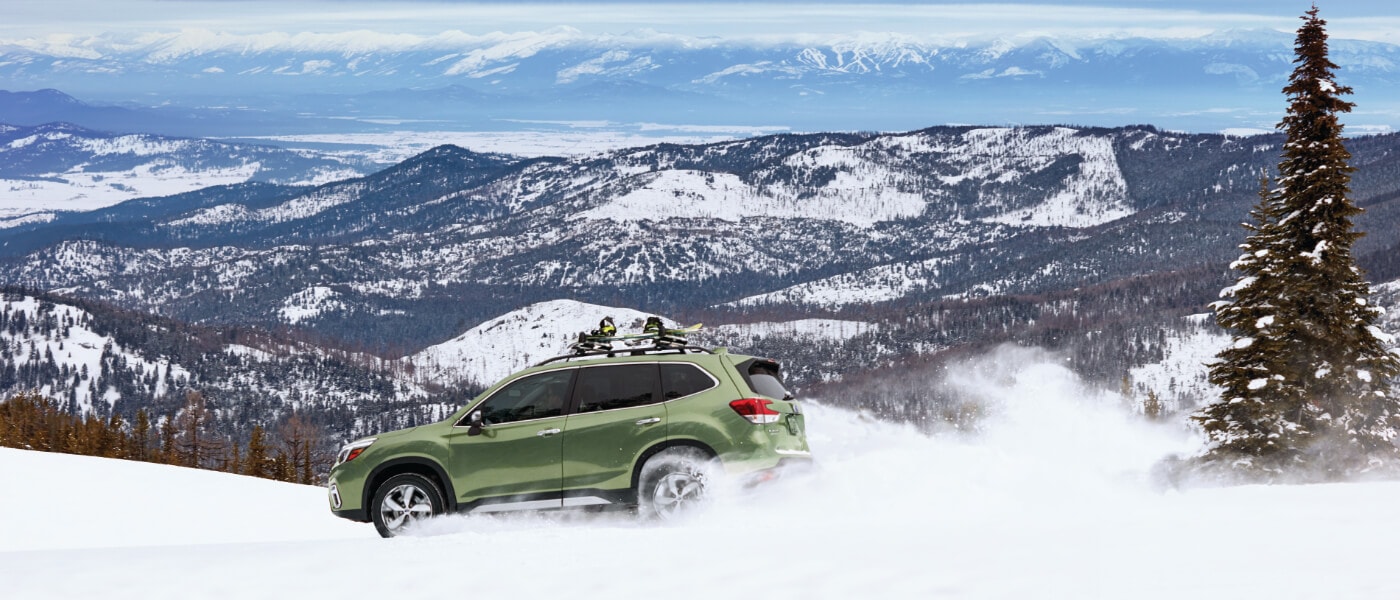 2020 Subaru Forester in green driving off road on snowing mountian