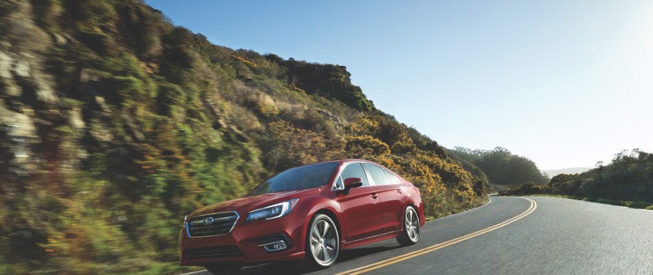 A Red 2018 Subaru Legacy Driving On An Open Road
