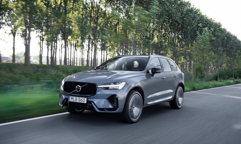 Volvo XC60 Recharge driving in front of trees