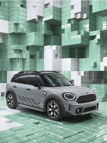 Three-quarter top view of a MINI Countryman Untamed Edition, showcasing its piano black exterior details, and black roof and mirror caps, in a CGI world made up of 3D, Tetris like boxes.